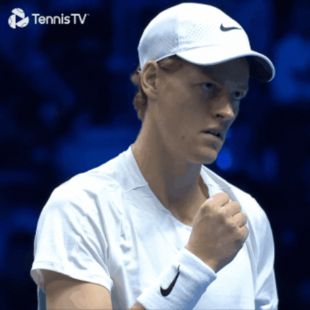 Sports gif. Tennis player, Jannik Sinner, clasps his fist closed with a look of determined satisfaction in his eyes.