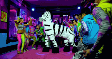 Video gif. We slowly zoom out of a flashy and colorful dance party, where two people trotting in place in a zebra costume are the center of attention.