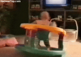 Video gif. A baby in a stationary rocker seat spinning around rapidly.