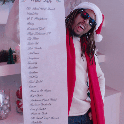 Music video gif. Lil Jon in his music video for All I Really Want For Christmas. He has shades and a Santa hat on he holds out a long wish list filled with items, sticking his tongue out in the background.