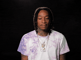 Celebrity gif. Wiz Khalifa shrugs his shoulders and scrunches his face, raising his eyebrows.