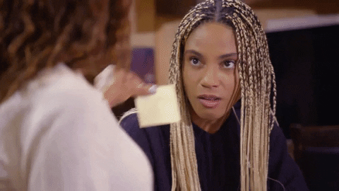 Gif of a woman sticking a post-it note to another woman's forehead.