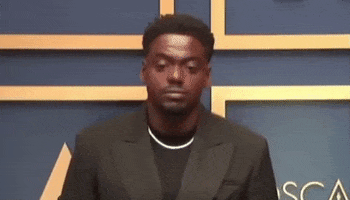 Celebrity gif. Daniel Kaluuya looks around, zoning out as if trying to remember something at the Academy Awards in 2021.