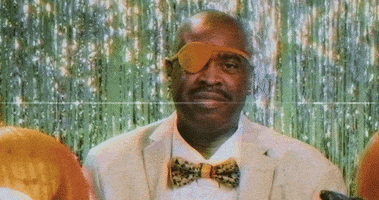 Celebrity gif. Slick Rick looks at us, smiling, and holding his hand in the “Okay” symbol.