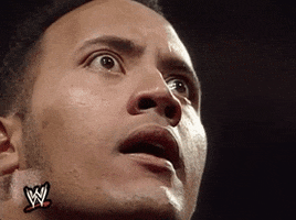 Celebrity gif. Dwayne The Rock Johnson on WWE stares with wide angry eyes and nods his head as if solidifying his threat. 