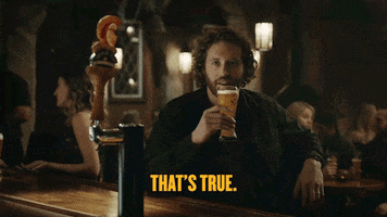 Ad gif. A man sits at a bar and laughs as he holds his glass of beer near his face. The little Shock Top orange mascot sits on a Beer tap handle also laughing, Text, “That’s true.”