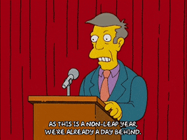 The Simpsons gif. Principal Skinner stands at a podium on a stage in front of a red curtain in what looks like a school auditorium, talking to a microphone and gesturing emphatically saying, "As this is a non-leap year, we're already a day behind."