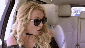 Celebrity gif. Britney Spears's hands cover her dropped jaw as if in shock as she sits near someone in a car. 