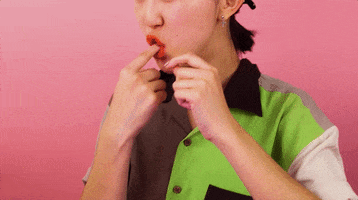 Video gif. Closeup of a well-manicured woman unstuffing a slice of white bread from her mouth.