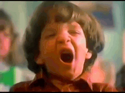 TV gif. Grainy, warm-toned '90s era footage of a child with a bowl cut yawning wide.