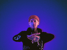 Music video gif. Standing in front of a dark blue background and wearing a black hoodie, Blackbear waves his hands, and the word "Anxiety" appears between them.