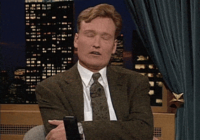 TV gif. Conan O'Brien sits arms crossed, staring at the camera while shaking his head in disapproval. He rolls his eyes annoyingly and looks back at the camera. 