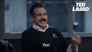 TV gif. Jason Sudeikis as Ted Lasso points affirmatively to someone behind the camera, emphatically saying what the text reads, "Yes!"