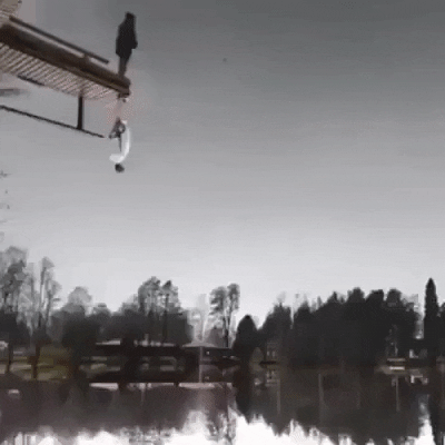 Video gif. A diving board appears to hang over a large lake, but there's something strange about it. The diving board and person standing on it is mirrored vertically, the double person hanging upside-down. Both mirrored forms take off their jacket, and swing their arms back to prepare to dive. Instead of jumping, they take off running, floating impossibly in the sky all the way across the lake.