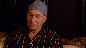TV gif. Patrick Stewart as Walter Blunt in Blunt Talk. He sits in a luxurious bed with a crochet beanie on and raises a glass at us proudly to cheers.
