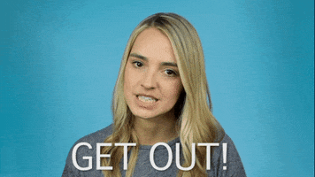 Video gif. Katelyn Tarver, a singer, stares at us seriously and dauntingly. She  demands us to, "Get out!"