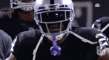 Sports gif. Football player Marshawn Lynch lowers his head in disappointment while standing at the sidelines during a game.