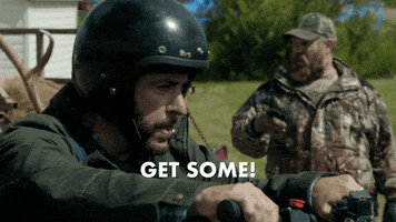 TV gif. Jason Jones as Nate in The Detour. It's a bright sunny day but he revs the engine on his snowmobile and snarls as he yells, "Get some!" while his friend watches in the back.