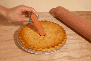 Digital art gif. A woman's hand inserts an uncooked hot dog through the small vent of a double-crusted pie, in and out, in and out.