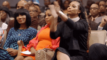 Reality TV gif. Tamar Braxton in Braxton Family Values. She's sitting in the audience with the rest of her family and she's clapping her hands enthusiastically while pursing her lips, in full support of what's being presented.