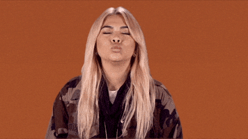 Celebrity gif. Hayley Kiyoko closes her eyes and gives us a bunch of kisses.