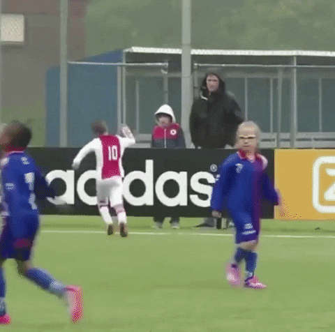 Sports gif. Young Ajax soccer player does the Ronaldo celebration by leaping in the air and shouting "woohoo" while landing with his legs spread apart and his fists clenched.