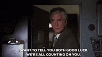 Movie gif. Leslie Nelson as Dr. Rumack in Airplane leans through the cockpit door and nods firmly as he says, “I want to tell you both good luck. We're all counting on you.”