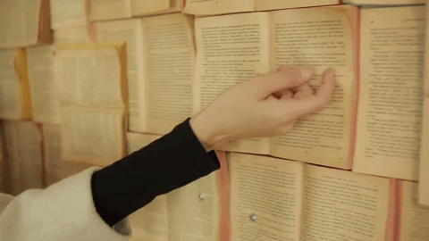 a person is picking up a book from a wall of books .