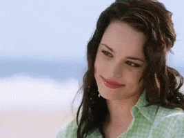 Movie gif. Rachel Mcadams as Claire Cleary in The Wedding Crashers tilts her head and looks over at someone with loving eyes. She nods and then bites her lip. Behind her, waves crash onto the beach. 