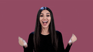 Celebrity gif. Victoria Justice does a happy dance, waving her fists in the air while jumping and grinning.