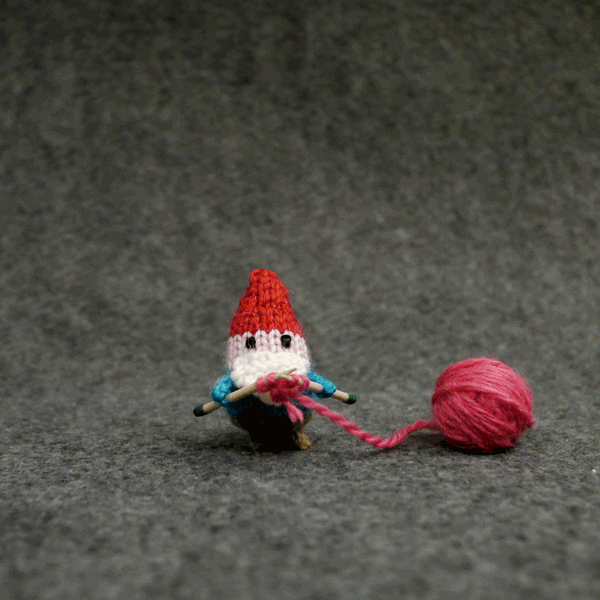 Stop-motion gif. A knitted gnome uses pink yarn to knit a small heart that floats up when it's finished.