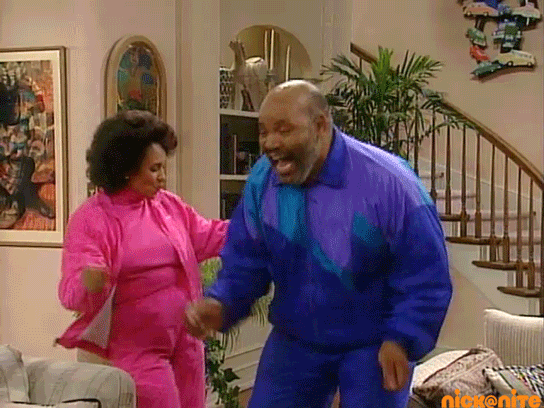 TV gif. Jane Hubert as Aunt Viv and James Avery as Uncle Phil from the Fresh Prince of Bel Air celebrate and dance with joy ins brightly colored tracksuits.