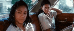 Movie gif. Jada Pinkett Smith as Stony in "Set It Off" sits in the backseat of a car, gazes out the window looking blank and unaffected, flipping her hand into a peace sign and smirking slightly.