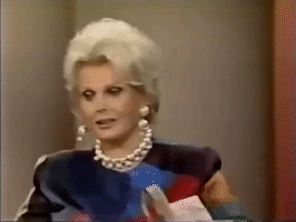 Celebrity gif. Donning pearl jewelry, Zsa Zsa Gabor elegantly rests her head upon her ring-adorned hand and contemplates something without losing her poise.