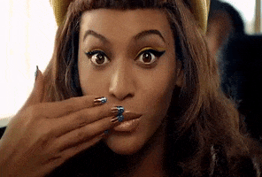 Music video gif. From video for Telephone, Beyonce looks at us with her hand covering her mouth and then glancing down to a plate of waffles being covered with syrup.