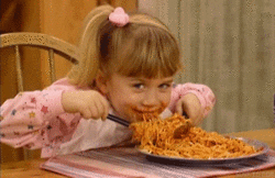 TV gif. Mary Kate or Ashley Olsen as Michelle in Full House holds utensils in both hands as she shovels spaghetti in her mouth with a grateful grin. 