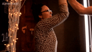 Reality TV gif. Contestants from Blown Away give each other a happy high five and one of them says, "Proud of you."