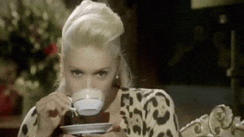 Celebrity gif. Gwen Stefani stares at us while raising a teacup to her mouth. She takes a sip and lowers the cup, smirking at us.