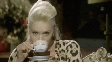 Celebrity gif. Gwen Stefani stares at us while raising a teacup to her mouth. She takes a sip and lowers the cup, smirking at us.