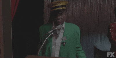 TV gif. Billy Porter as Pray Tell from Pose stands in front of a shimmering curtain, wearing a bright green suit, pastel green necktie, and a gold captain's cap. He says "Goodnight" into a microphone, and that is the only thing he wishes to share.