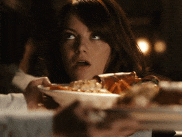 Movie gif. Emma Stone as Olive Penderghast from Easy A rolls her eyes in pleasure and opens her mouth as a plate of food is set down in front of her.