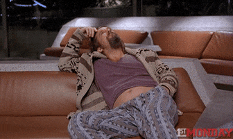 Movie gif. Jeff Bridges as The Dude in the Big Lebowski reclining on a couch, lazily stroking his forehead and bobbing his knee.