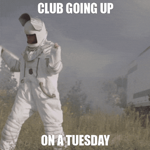Video gif. A person wearing a spacesuit with the visor up, appears to dance in a field as they walk through it, hands above their shoulders. We can see smoke in the background. Text, "Club going up on a Tuesday."