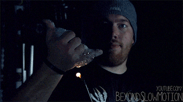 Video gif. Man wearing a beanie lights up his hand in a shaka sign in slow motion, then shakes it out.