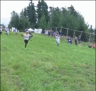 Gif of a white woman in safety gear running down a hill (posibly a cheese rolling festival) and spectacularly face-planting in the grass