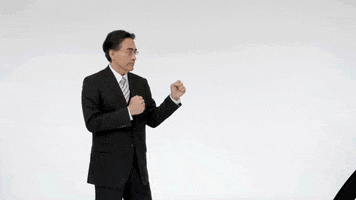 Celebrity gif. Satoru Iwata punches an animated cup off-screen.