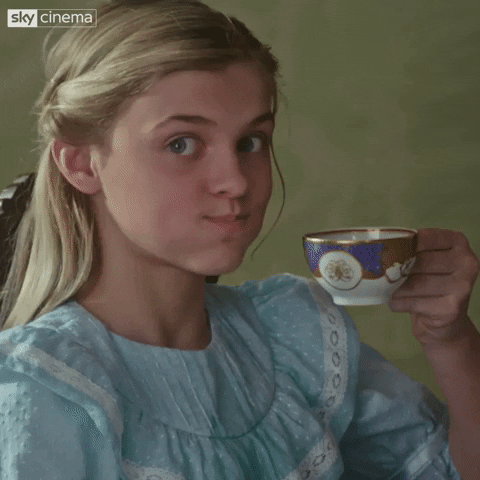Video gif. A girl in a light blue dress looks at us with a mouthful of tea, and laughs her way into a spit take.