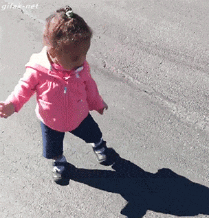 Video gif. Toddler sees her shadow for the first time and it freaks her out. She tries to run from it, failing, and she cries and falls over.