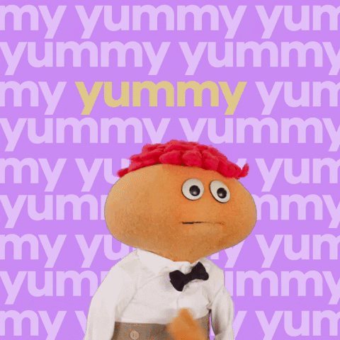 Video gif. Gerbert an orange puppet with orange hair, looks at us while bopping his round head. He opens his mouth to speak and we zoom in super close to his face. The background says, “Yummy.” over and over.