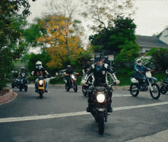 Celebrity gif. On motorbikes, The Kid Laroi, Juice WRLD, and a crew of motorcyclists ride toward us.